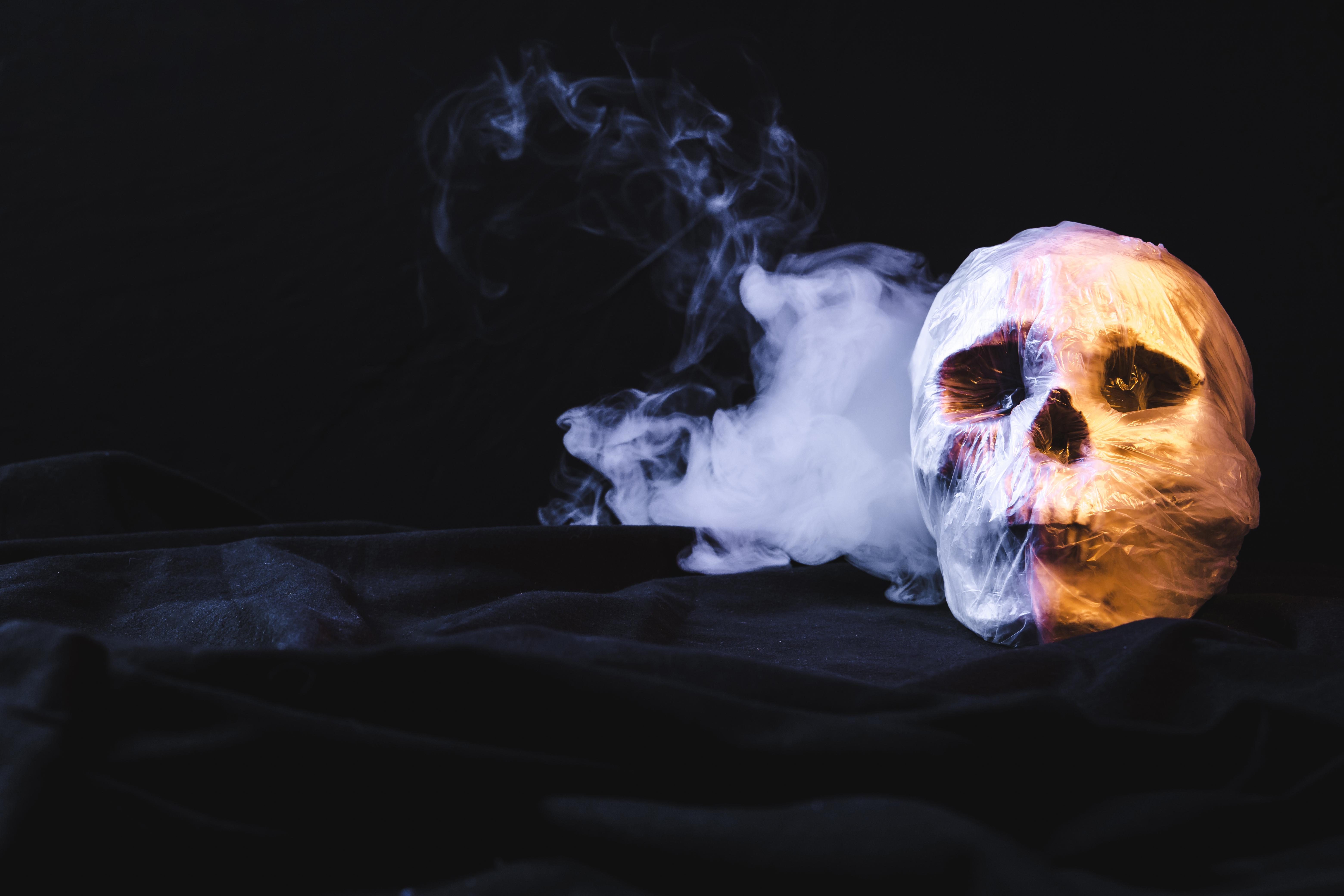 Rituale esoterico con un teschio avvolto in un sacchetto di plastica con fumo.